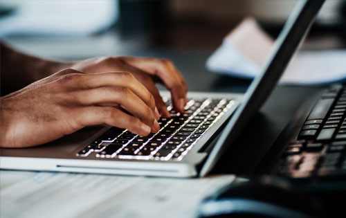 Hands typing on a laptop