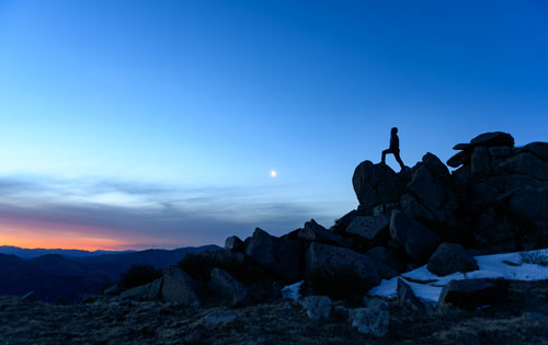 stock-photos Person standing on rock overlooking blue mountain skyline