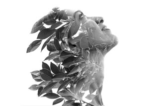 Double exposure portrait of a woman with leaves flowing through her silhouette